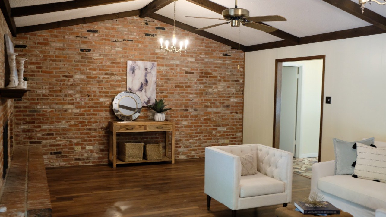 Warm residential interior with exposed brick, wood beams, and a white sofa.